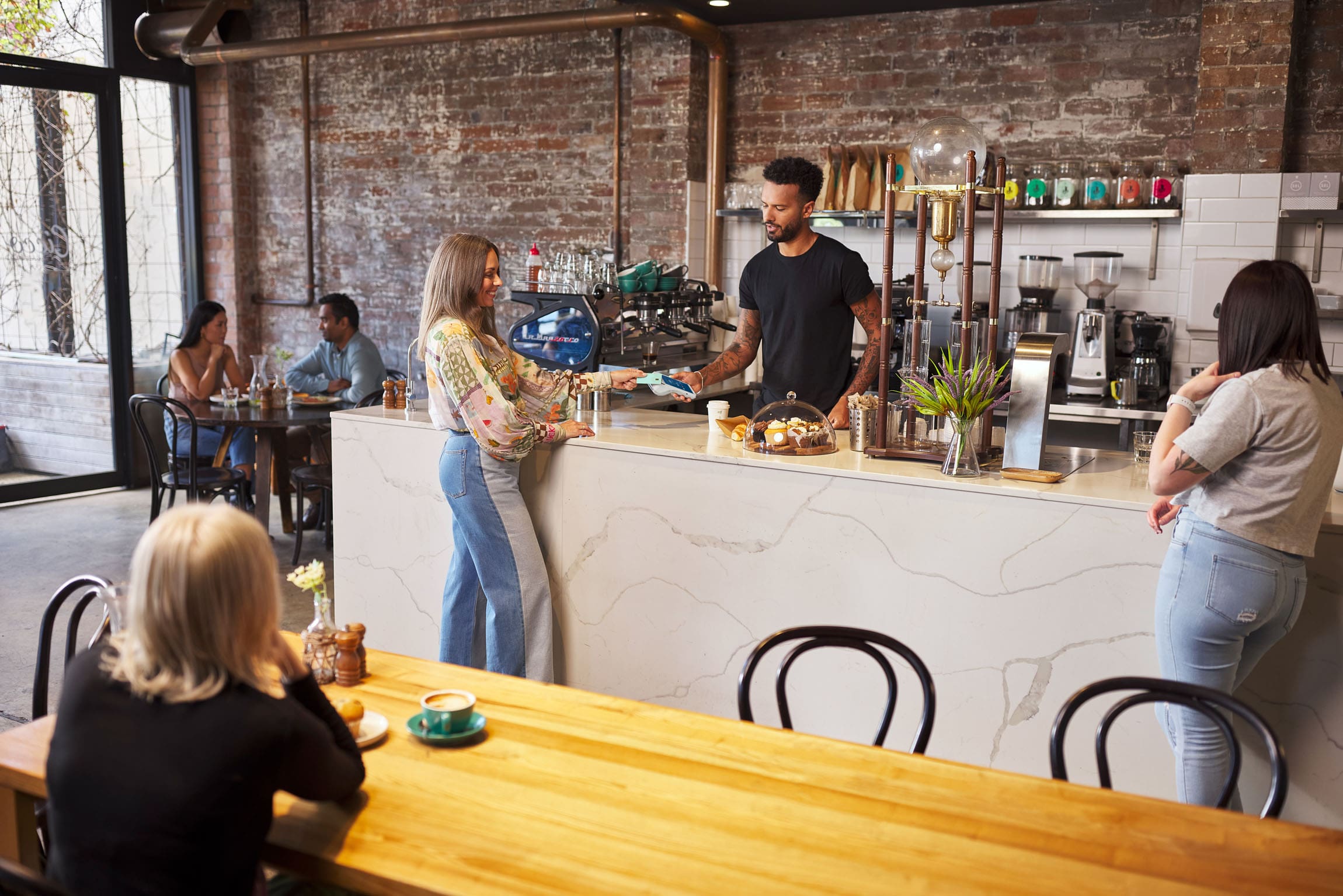 Wide show of women tapping card on Android terminal at Cafe