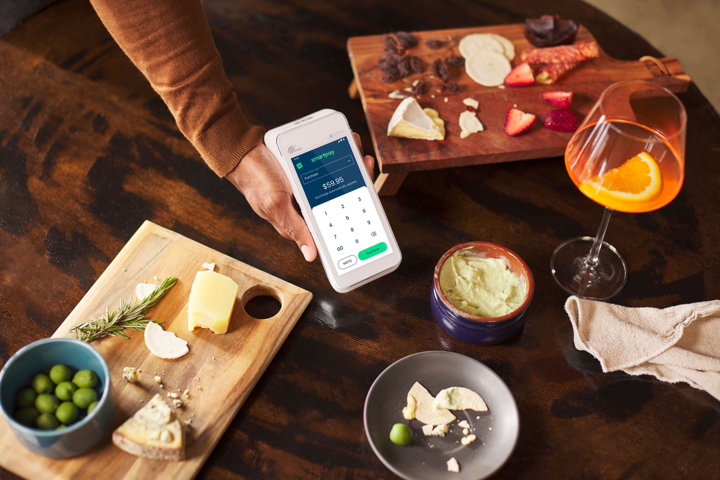 Hand holding Android terminal on top of wooden table with different food items