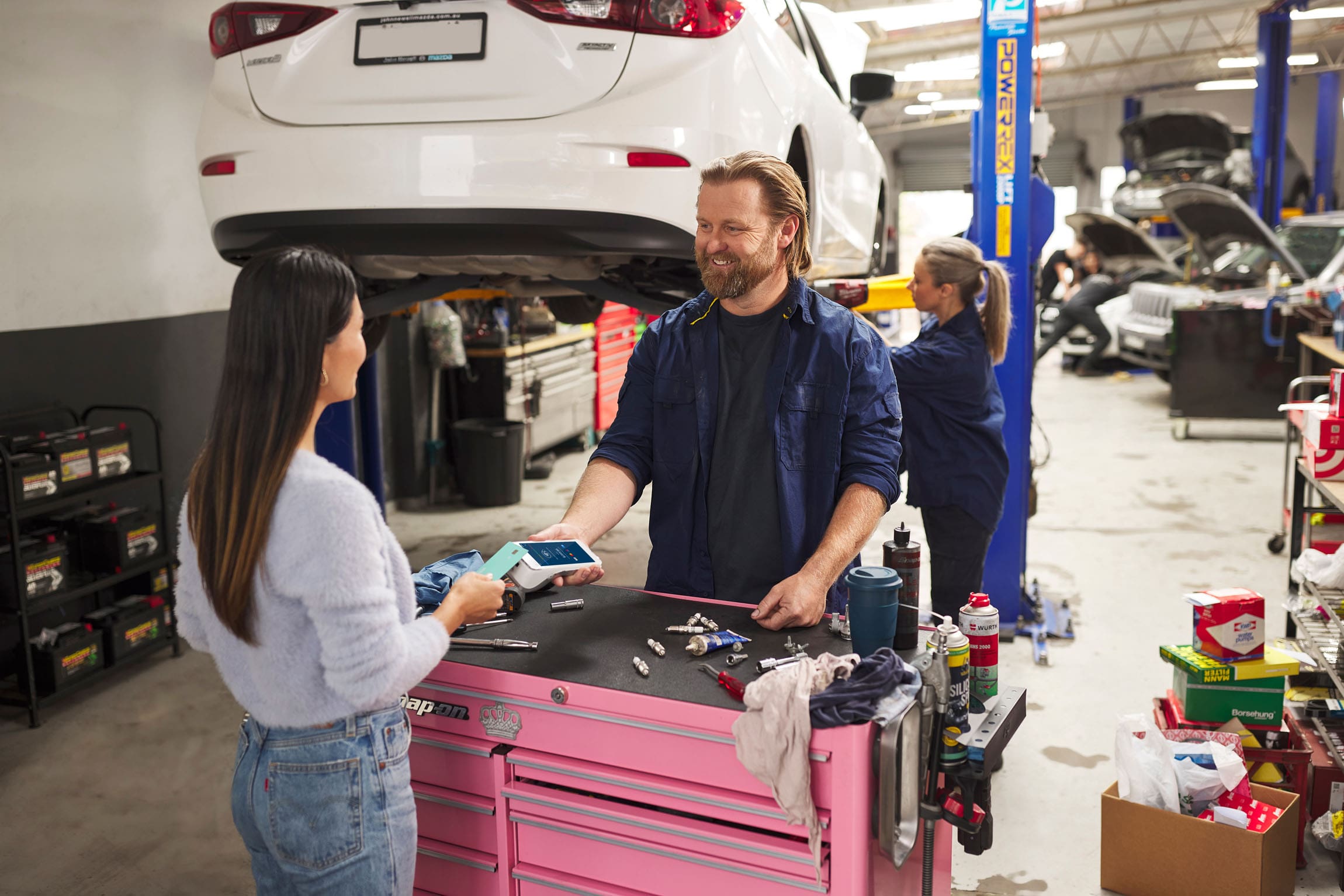 Wide shot of Women tapping card on Android terminal at a mechanic