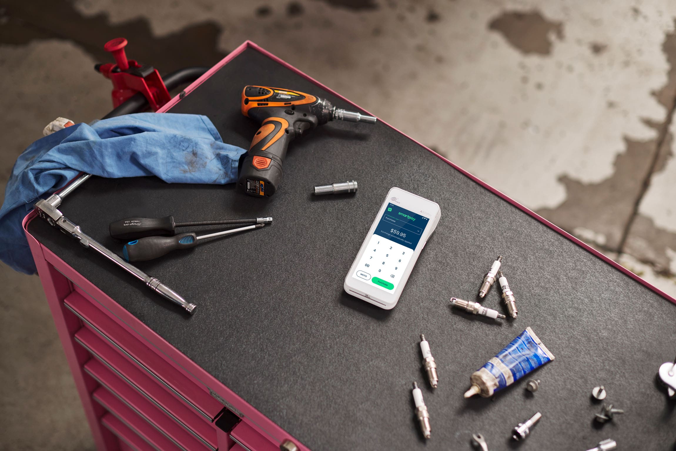 Smartpay Android terminal sitting on tool bench surrounded by mechanic accessories