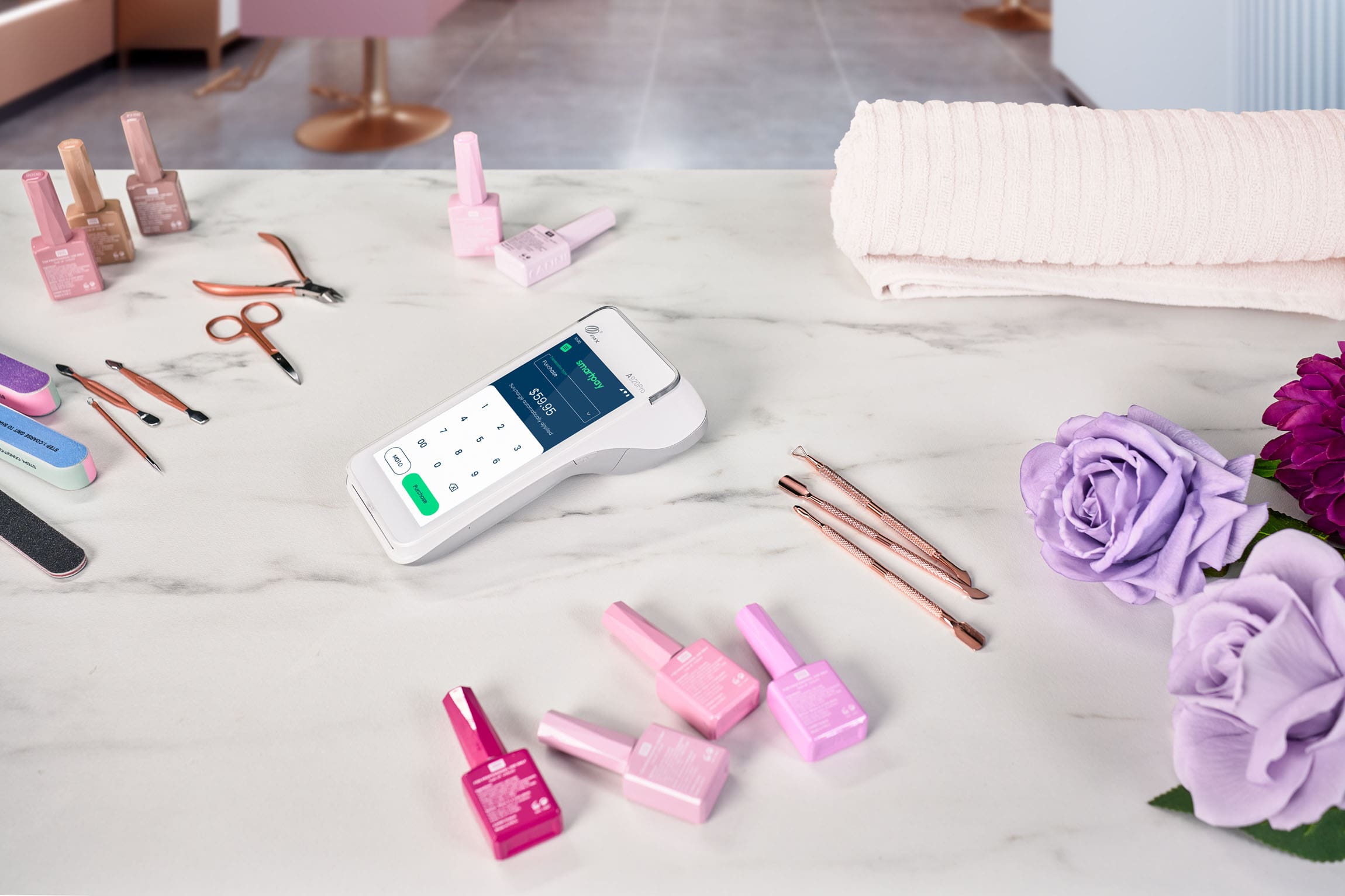 Android terminal sitting on marble table surrounded by nail salon accessories