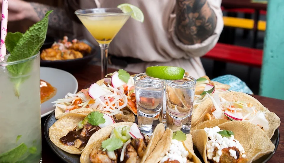 a plate of tacos and shot glasses